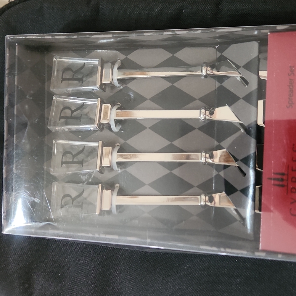 NEW IN BOX SET OF 4 INITIAL DESIGN BUTTER SPREADERS.